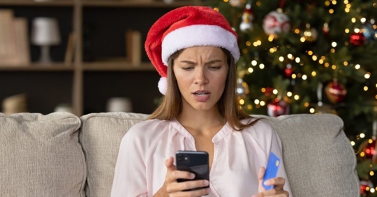 Woman looking at phone while holding credit card.