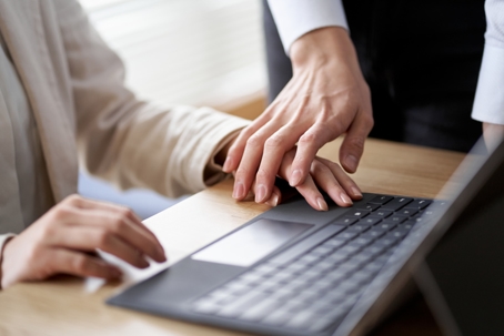 A person placing their hand over another person’s hand on a laptop keyboard, suggesting unwanted physical contact at work. | Gaines & Gaines, APLC