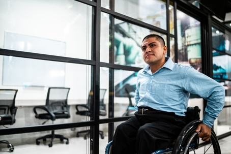 Young wheelchair man walking at office